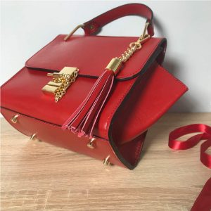 Kleine Ledertasche rot mit Henkel, Drehverschluss mit Kette in Goldoptic, Lederquaste abhembar. Henkeltasche mit Deckelklappe und Innenfach. Trapezform Tasche. Ledertasche mit Bodenfüße.