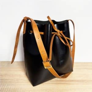 Zweifarbige Leder crossbody und Schultertasche schwarz mit cognacbraunem Riemen und Band. Mittelgroße Bucket bag mit einem längenverstellbaren, praktischen Riemen. Elegante. leichte Damen Ledertasche handgefertigt, geeignet für jeden Tag.