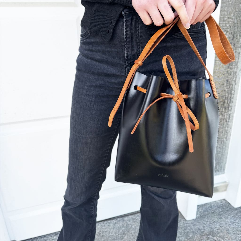 Zweifarbige Leder crossbody und Schultertasche schwarz mit cognacbraunem Riemen und Band. Mittelgroße Bucket bag mit einem längenverstellbaren, praktischen Riemen. Elegante. leichte Damen Ledertasche handgefertigt, geeignet für jeden Tag.